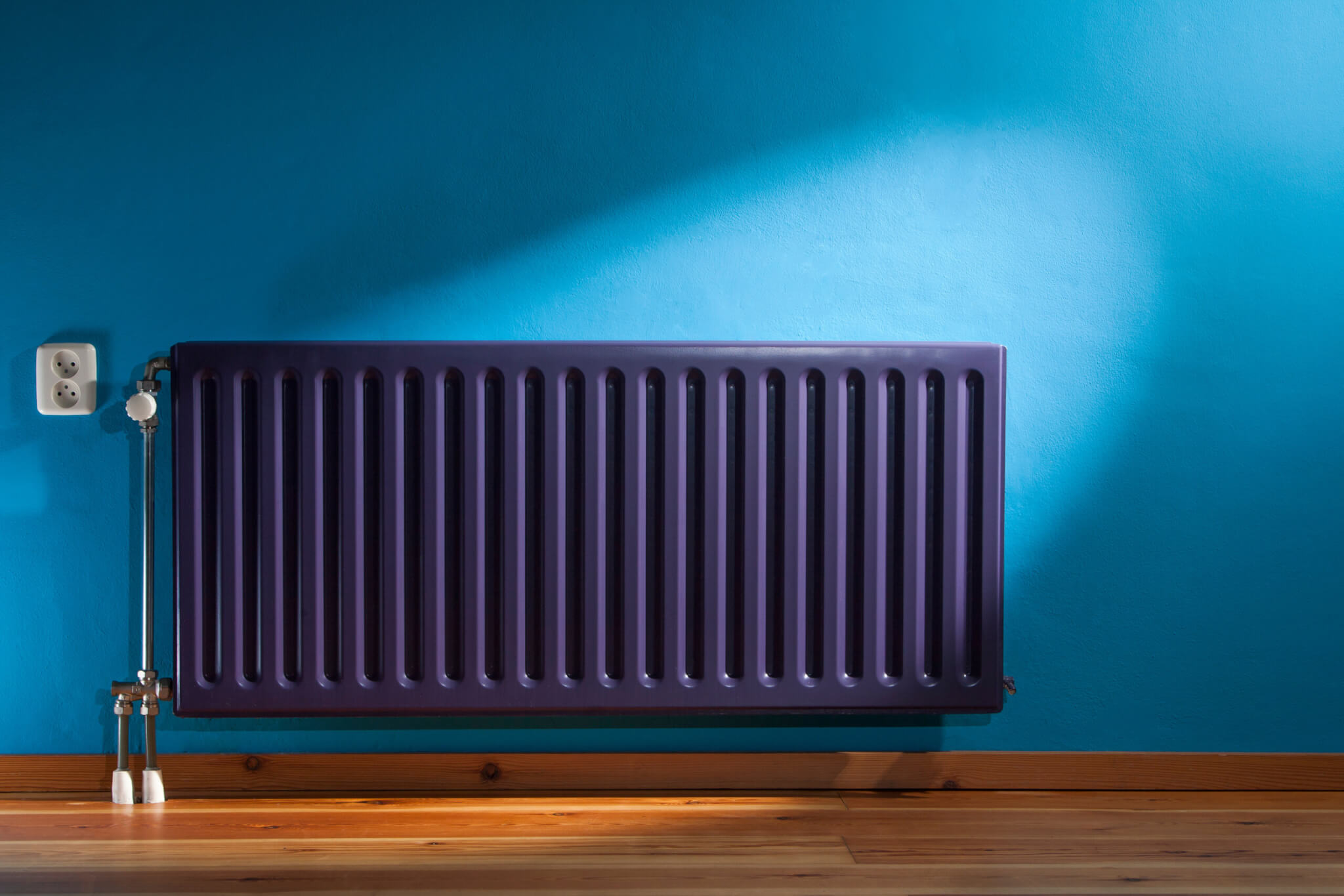 Purple central heating radiator and a blue wall with power point in the Netherlands